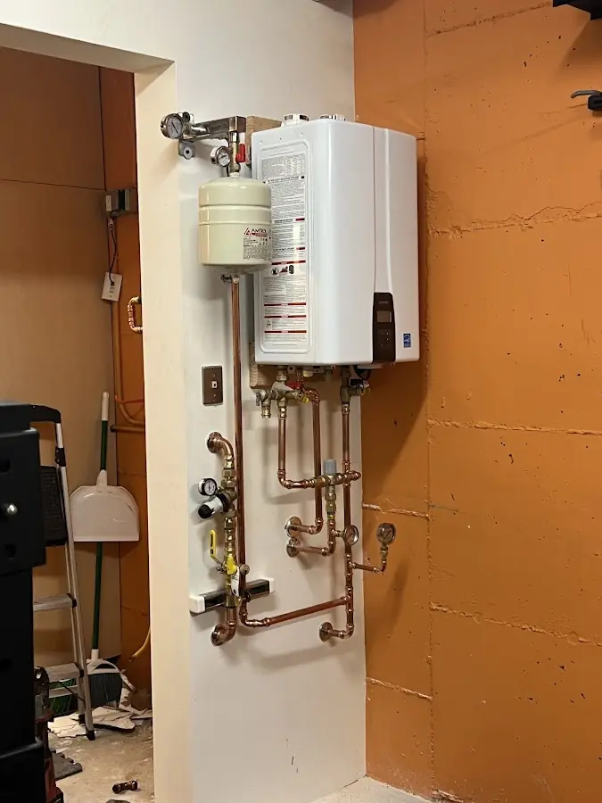 Plumbing technician inspecting water heater connections in Hingham